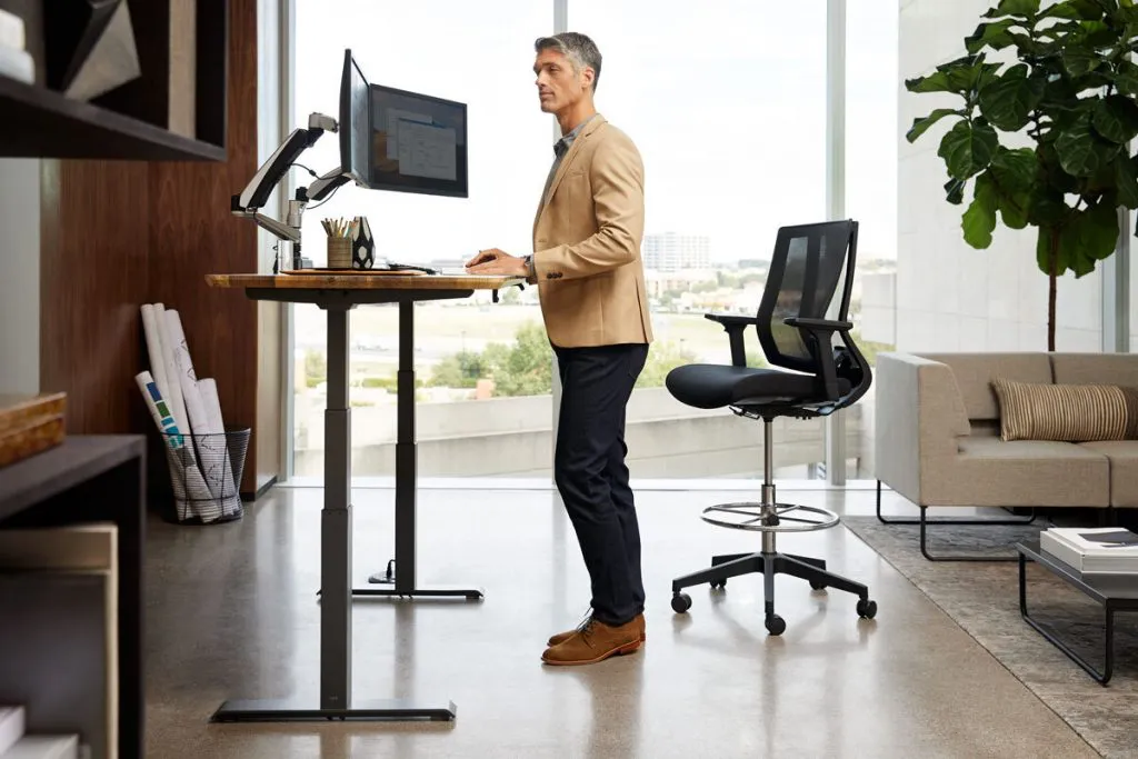 Worker using a sit-stand desk to alternate between sitting and standing